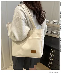 Primer plano del bolso tote de lona blanco hueso con bolsillos laterales y etiqueta de cuero