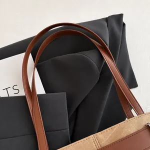 Detailed close-up of brown leather handles and premium stitching on a patchwork tote bag