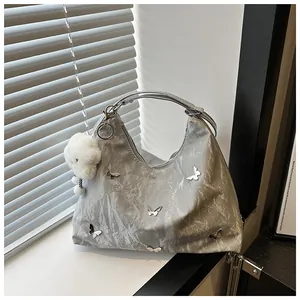 Detail of silver-grey tote bag with metallic texture, butterfly decor and plush cloud charm