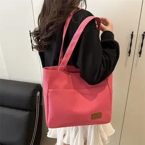 Bolso tote de lona rosa con correas al hombro llevado por modelo para un look casual