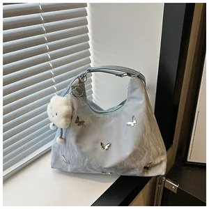 Close-up of light blue pleated bag with silver butterfly charms and cloud pendant