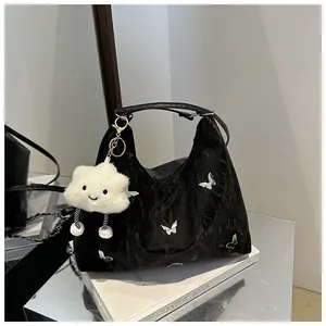 Close-up of black pleated patent leather bag with silver butterflies and plush charm