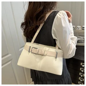 Elegante borsa sottobraccio beige con cinturino a contrasto e fibbia argentata su modella