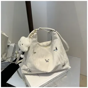 Detail of white pleated handbag with silver butterflies and plush cloud pendant