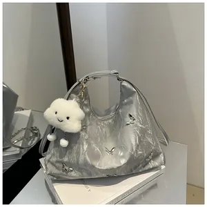 Detail of silver metallic bag with butterfly patches and plush cloud charm on white books