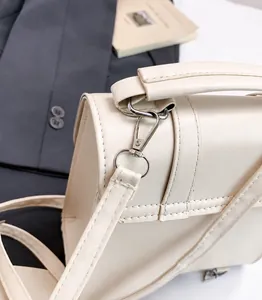 Close-up of premium silver buckle and precision stitching on beige PU leather handbag