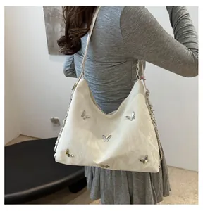 Detail of creamy shoulder bag featuring silver butterfly accents and soft leather texture
