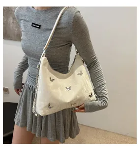 Detail of white hobo bag featuring silver butterfly charms and elegant pleated texture