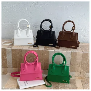 Dettaglio di mini borse a trapezio colorate con manici rotondi e logo dorato fine