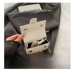 Detail van de witte mini leren tas met compacte opbergruimte en een gouden kettingriem