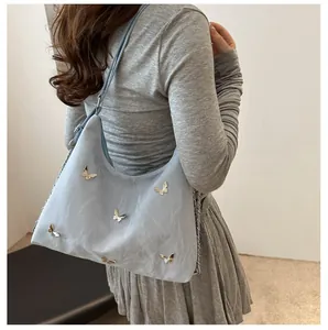 Detail of light blue Hobo bag featuring silver 3D metal butterflies and wrinkled texture