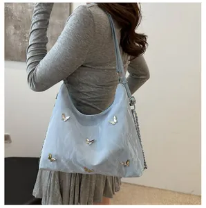 Close-up of light blue shoulder bag featuring silver butterfly metal accents and ripple texture