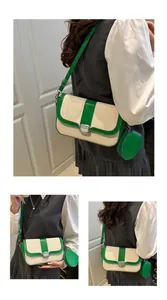 Detail view of woven saddle bag with green leather trim and round coin purse attachment