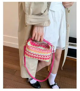 Dettaglio della borsa a tracolla colorata intrecciata con manico rosa e motivi geometrici