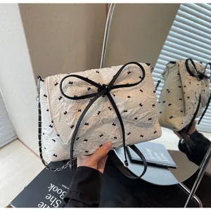 Detail view of the white quilted texture with black bow patterns and elegant metal chain