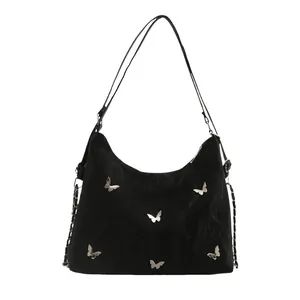 Large black hobo shoulder bag with silver butterfly charms and wide strap on white background