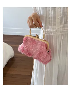 Detalle de bolso floral rosa con asa dorada llevado por modelo en vestido blanco