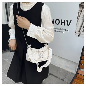 Detail of white pleated handbag with pearl strap and metal chain on a female model