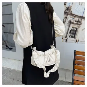 Detail view of cream ruffle shoulder bag featuring pearl and metal chain strap design