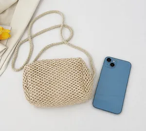 Gedetailleerde vergelijking van de beige gevlochten tas met een smartphone op wit decor