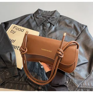 Detail of brown leather shoulder bag with FASHION & BAGS logo and knotted strap