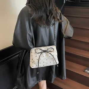 White quilted crossbody bag with black bow prints and silver chain strap for women