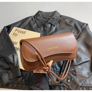 Detail of a brown leather shoulder bag with a gold Fashion & Bags logo and knot strap