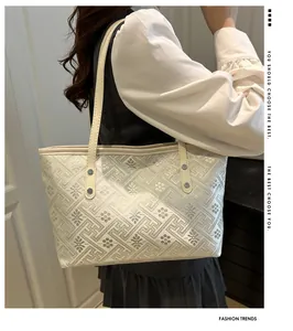 Detail der weißen Beuteltasche mit Blumenstickerei und silbernen Metallnieten