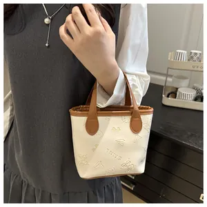Détails de l'embossage papillon sur le mini sac seau crème avec bordures marron chic