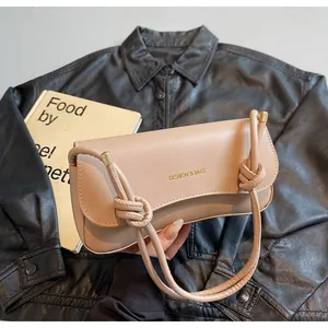 Detail of the chic beige underarm bag showing the knot strap and gold metal buckle