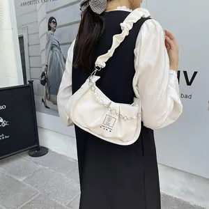 White ruched underarm bag with pearl flower chain shown in an outdoor fashion setting