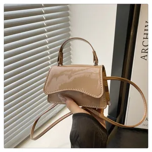 Detail of a khaki glossy patent leather mini bag featuring a stylish wavy flap cover