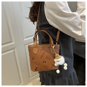 Détail du sac cabas en PU marron caramel avec motifs dessins animés et breloque