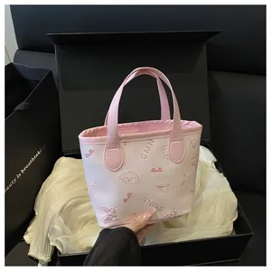 Détail du sac seau rose avec motifs papillons embossés placé dans un coffret cadeau noir
