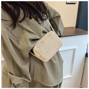 Detailweergave van een beige stro-geweven crossbodytas met kettingriem bij een model