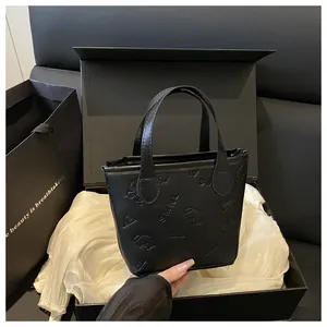 Détail d'un sac seau en cuir noir gaufré avec motifs de papillon et de chien en coffret
