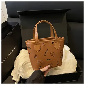 Gros plan sur un sac seau marron en cuir avec motifs embossés dans une boîte cadeau noire