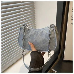 Close-up of light blue underarm bag with 3D floral texture and silver chain detail