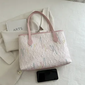 Detailopname van roze en witte stoffen draagtas met getextureerd borduurwerk en stiksels