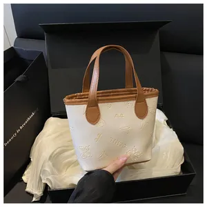 Détails de motifs papillon gaufrés sur un sac cabas crème avec des anses marron