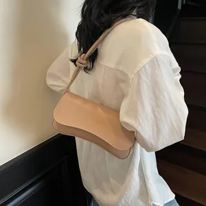 Chic beige underarm baguette bag with knotted strap and gold foil lettering detail