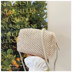Detail van handgeweven crèmekleurige crossbodytas met touwriem en metalen ritssluiting