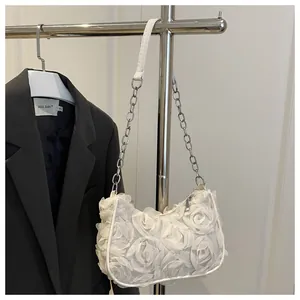 Detailopname van witte avondtas met 3D stoffen rozen en zilveren ketting schouderband