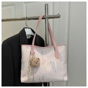 Detail van de roze shopper met golvend borduurwerk en een bruine pluche berenbedel