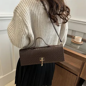 Elegante bolso baguette de cuero marrón oscuro con cierre dorado y correa ajustable