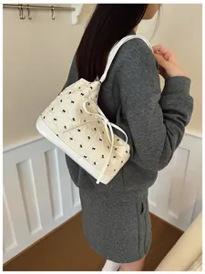 Détail du sac à bandoulière matelassé avec petits nœuds noirs et grand ruban blanc