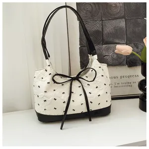 Détail du sac hobo montrant le tissu gaufré blanc aux motifs de petits nœuds