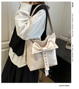 Detail of soft cream bucket bag featuring a large bow with silver stud accents