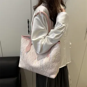 Roze-witte jacquard draagtas met golfborduurwerk en lederen hengsels aan een model