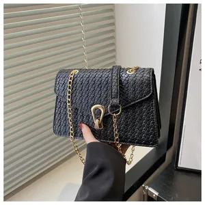 Close-up of black woven PU leather bag with golden horseshoe buckle and chain strap